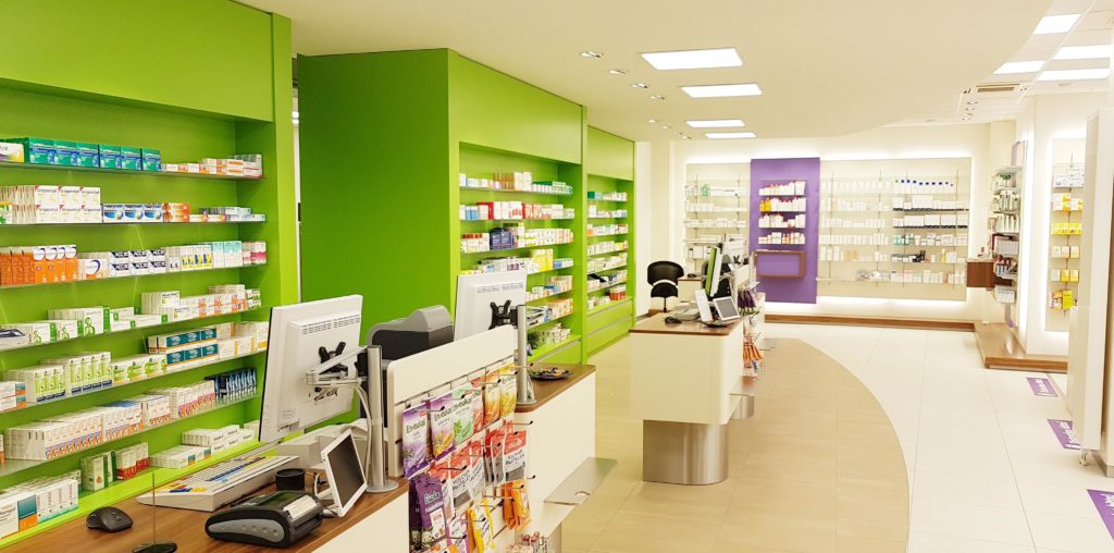 Apotheke mit Handverkaufstisch und grünen Regalwänden von APO-Interieur